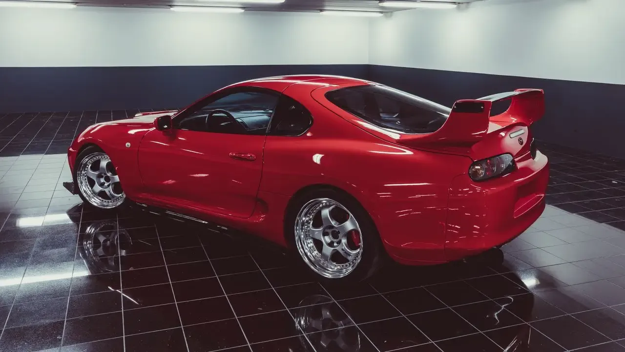 A red Toyota Supra Mk4 in a showroom