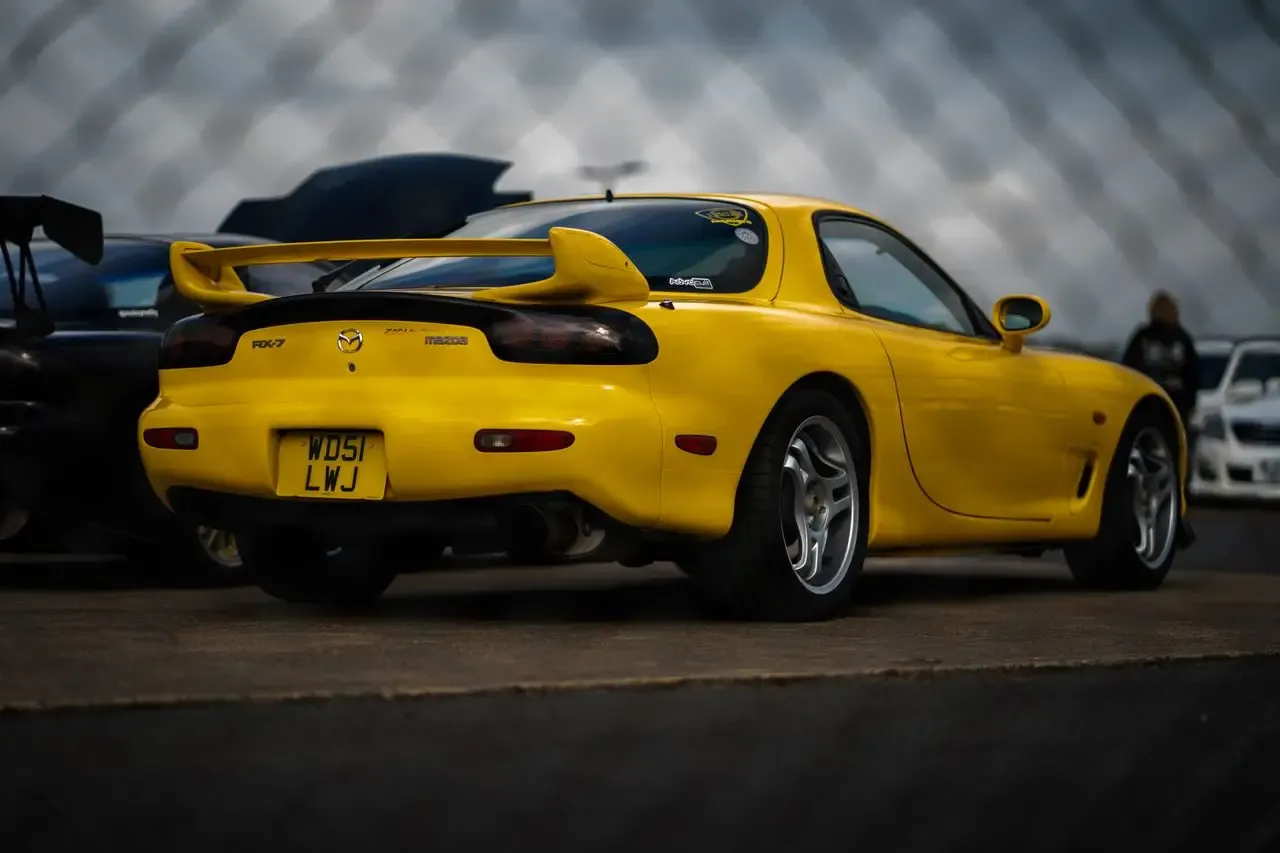 A yellow Mazda RX-7 FD, rear three-quarter